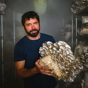 Picture of Chris Pacheco of Seacoast Mushrooms holding up mushroom