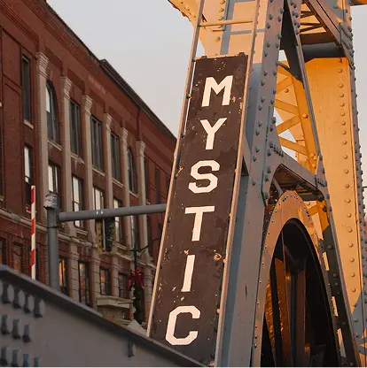 The iconic Mystic Bascule Bridge features a prominent sign with vintage architectural details at sunset.
