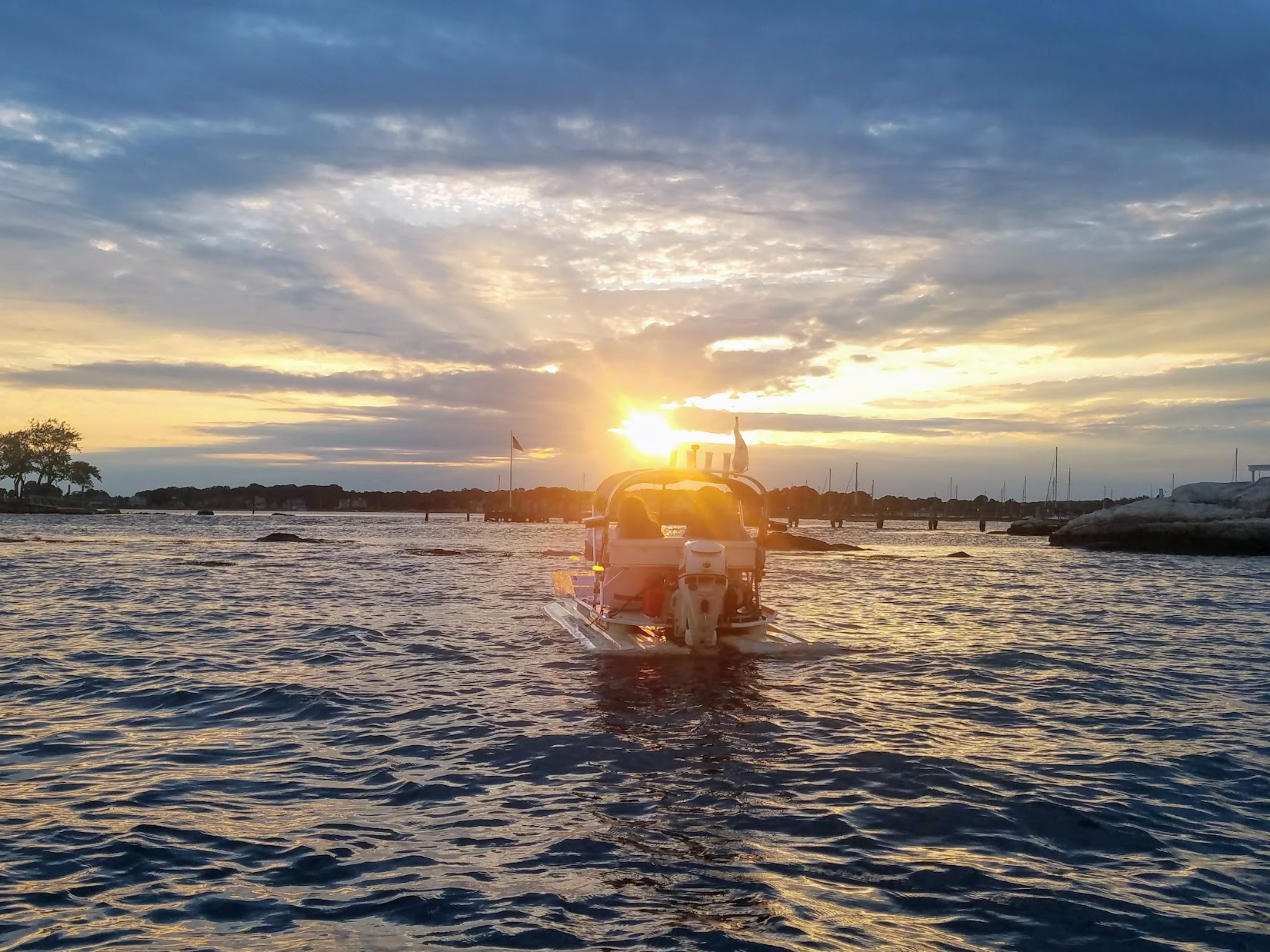 Small motorboat sailing on tranquil water during a beautiful golden sunset.