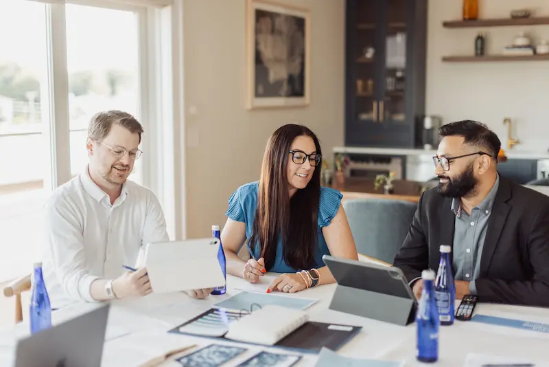 Three professional colleagues collaborate on a project during a productive business meeting in a modern office space.