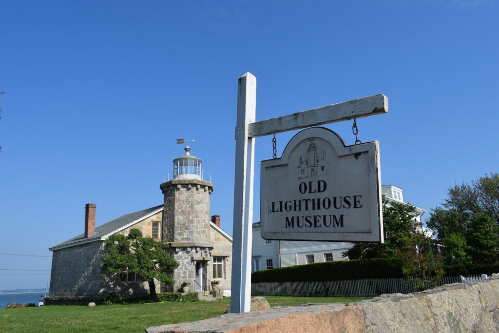 Historic stone lighthouse against a clear blue sky on a sunny day.