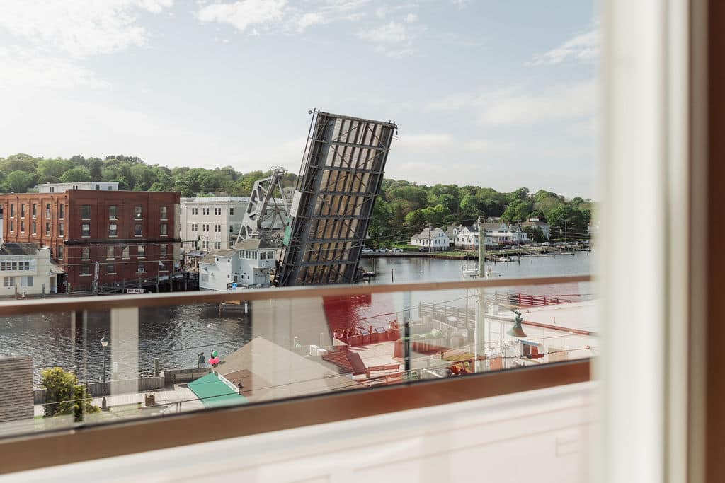 View of the Mystic River drawbridge in Connecticut from a window with a glass balcony railing.
