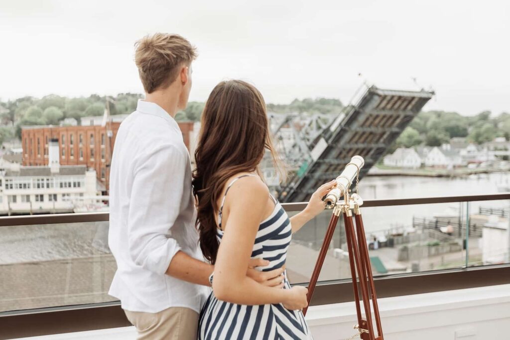 A young couple looking through a telescope from a balcony at a bridge in Mystic, Connecticut.