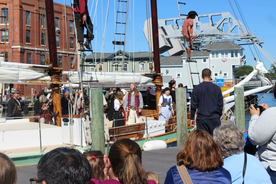 A group of people dressed as pirates stand aboard a Schooner Sailboat 