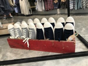 A display of tennis sneakers in a wooden shallow box.