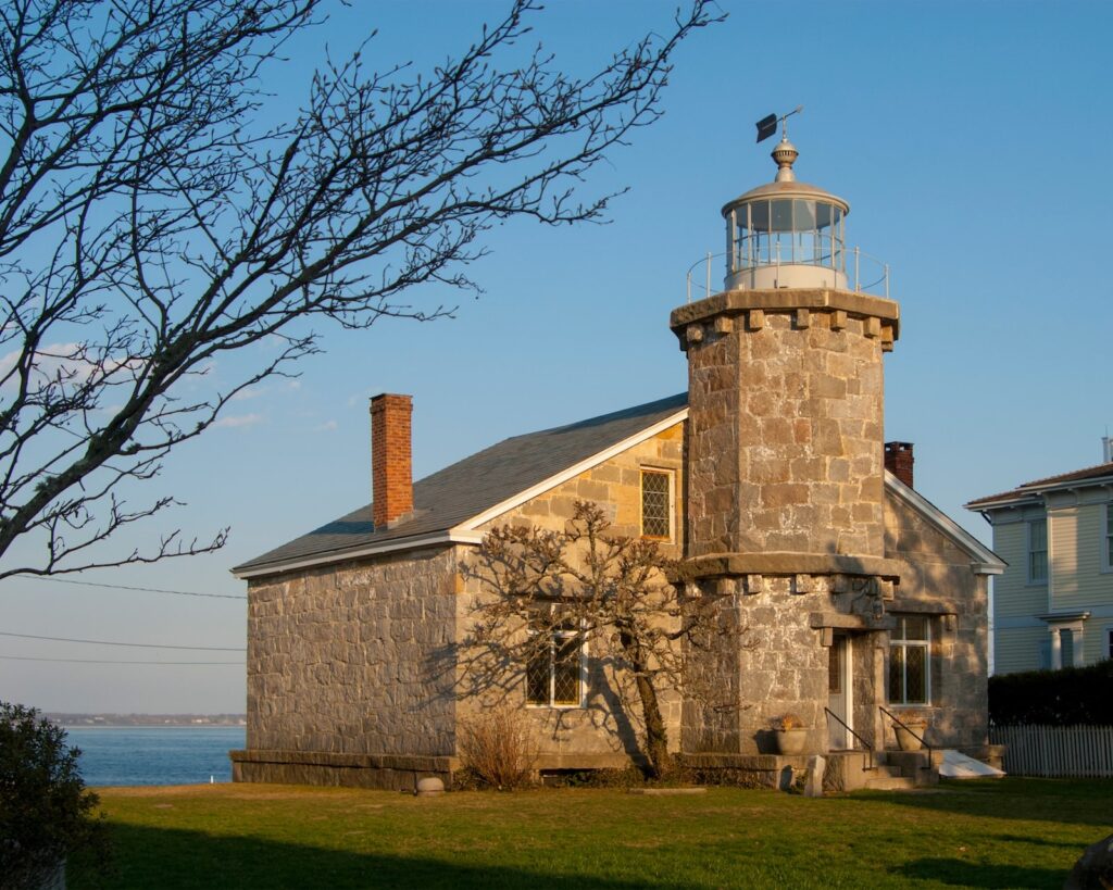 Historic stone lighthouse against a clear blue sky on a sunny day.