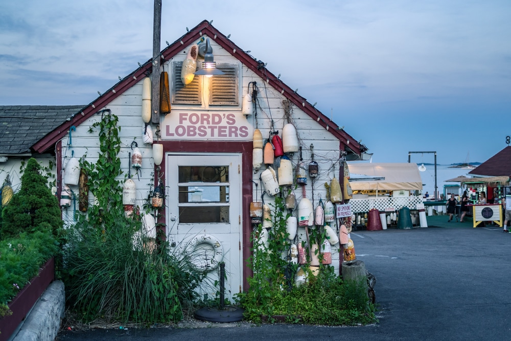 Ford's Lobsters seafood shack decorated with colorful fishing buoys at a waterfront harbor location.