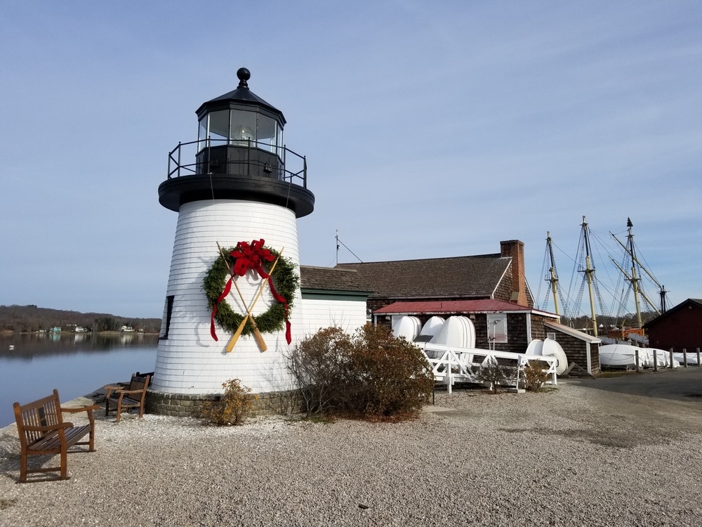 Mystic Seaport Museum lighthouse decorated for the holidays with a Christmas wreath on the shore.