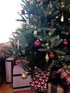 A christmas tree with gifts wrapped beneath it set up for ushering in the holiday season