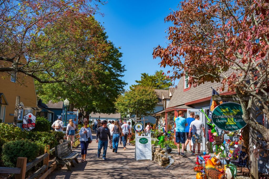 People walking between shops and fall foliage in Mystic, CT, on a weekend getaway in New England.
