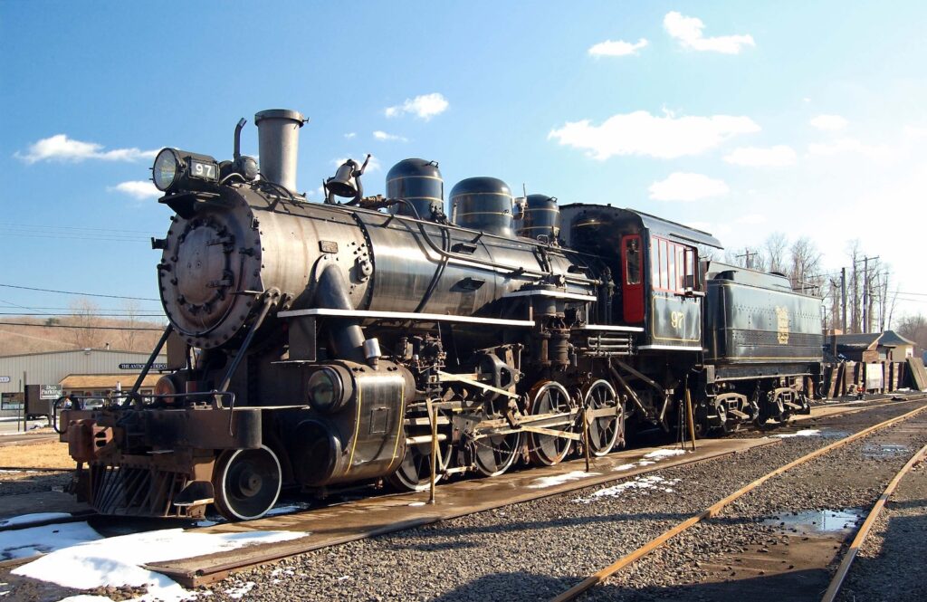 The Essex Steam Train on the tracks with snow on the ground and blue skies in Essex, CT.